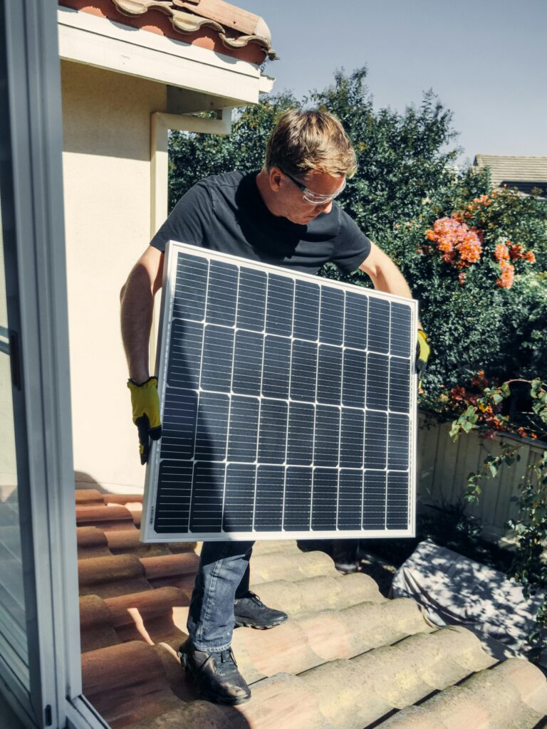 pexels-photo-9875444-9875444 A worker installs a solar panel on a roof, promoting clean and renewable energy.